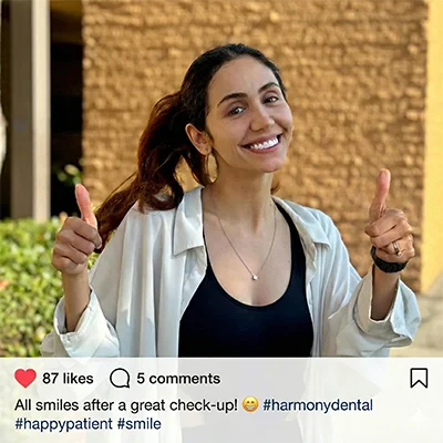 A happy, smiling patient standing outside the Harmony Dentalcare clinic after a comfortable and successful dental visit